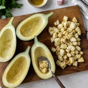 Eggplant halves are hollowed with a spoon, with chopped eggplant flesh set aside for the filling.