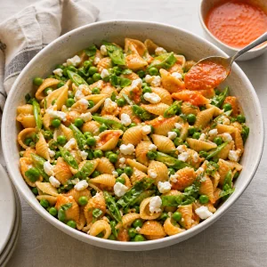 Insalata di pasta servita con un cucchiaio di vinaigrette al peperone
