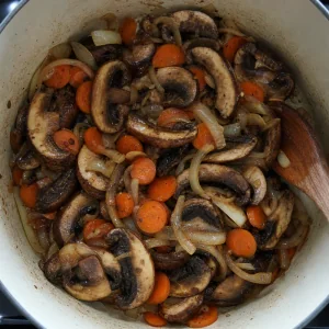 Fette di portobello in cottura con carote e cipolle