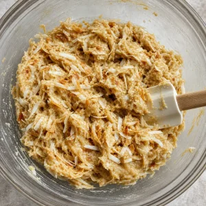 Coconut flakes folded into thick cookie dough