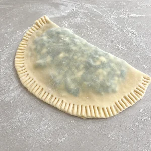 Folded gozleme dough sealed around the spinach and feta filling