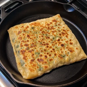 Gozleme cooking in a dry skillet until golden and blistered