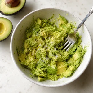 Stueckig zerdrueckte Avocado mit Olivenoel in einer Schuessel
