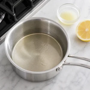 Lemon syrup cooling in a saucepan with fresh lemon nearby