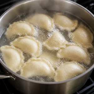 Half-moon varenyky floating in gently boiling water.
