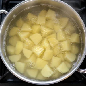 Potato chunks boiling in a saucepan for the varenyky filling.