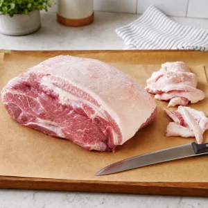 Paleta de cerdo cruda recortada en una tabla con una fina capa de grasa