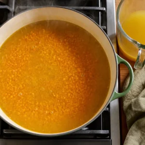 Lentilhas vermelhas e caldo de legumes a fervilhar numa sopa dal dourada