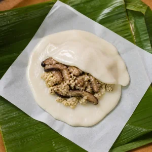 Reisteig und Pilz-Tofu-Fuellung werden auf einem Bananenblatt geschichtet
