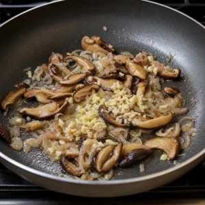 Schalotten, Knoblauch und Shiitake-Pilze duensten in der Pfanne