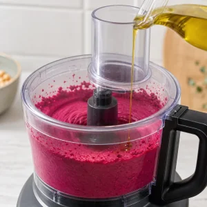 Olio d oliva versato in un paté magenta liscio di barbabietola e ceci
