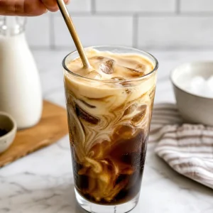 Geschlagener Honigschaum wird sanft in den Eiskaffee geruehrt