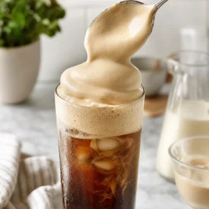 Geschlagener Honigschaum grosszuegig auf Eiskaffee geloeffelt